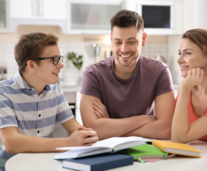 Young teen son at the kitchen table doing homework with help from his Dad and Mom.