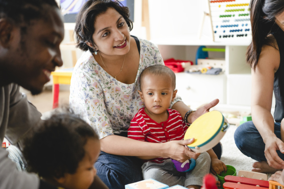 Parents with young children sitting on their laps playing together.